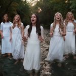 Nine Women Line Up In A River.