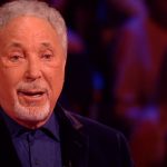 Tom Jones with tearful eyes stands up and sings