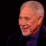 Tom Jones with tearful eyes stands up and sings
