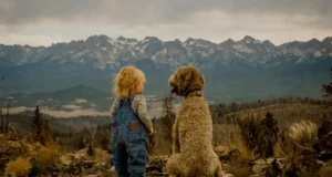 A child and dog sit together facing a vast mountain range, enjoying a serene moment..