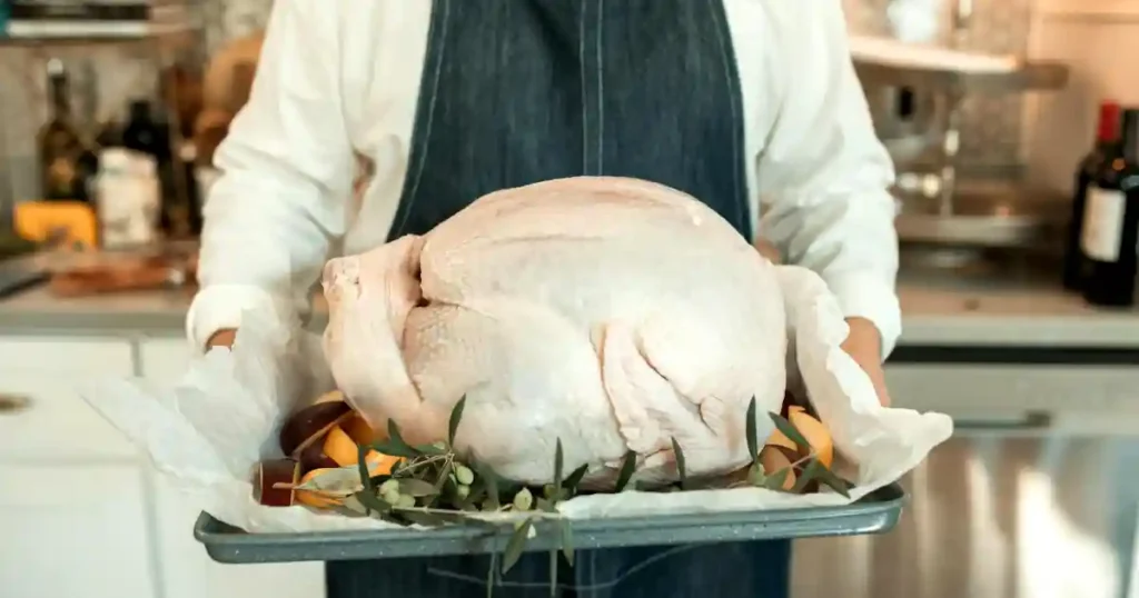 A fresh turkey on a tray, ready for cooking, embodies the Thanksgiving spirit indoors..