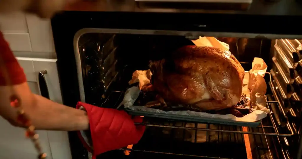 A golden roasted turkey being taken out of the oven, ready for a Thanksgiving feast