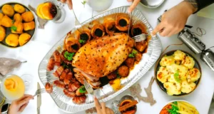 Top view of a festive holiday dinner table with roast turkey, sides, and drinks..