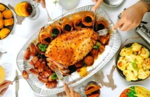 Top view of a festive holiday dinner table with roast turkey, sides, and drinks..