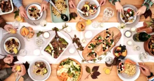 Overhead shot of a vibrant dining table setup with pasta, salads, and decorative candles, capturing a festive gathering..