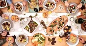 Overhead shot of a vibrant dining table setup with pasta, salads, and decorative candles, capturing a festive gathering..