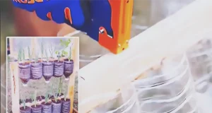 A DIY vertical garden made from recycled plastic bottles attached to a wooden frame, filled with soil and small green plants for a space-saving garden project.