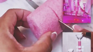A pink pool noodle bathtub water wall with white funnels taped to bathroom tiles above a colorful bath setup, creating a fun DIY glow bath play area for kids.