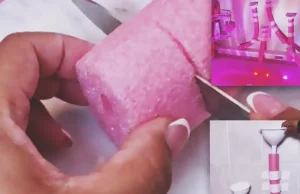 A pink pool noodle bathtub water wall with white funnels taped to bathroom tiles above a colorful bath setup, creating a fun DIY glow bath play area for kids.