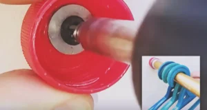 A red plastic bottle cap mounted to a wall and holding a gold wardrobe rail with blue clothes hangers.