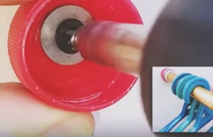 A red plastic bottle cap mounted to a wall and holding a gold wardrobe rail with blue clothes hangers.