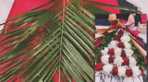 A luxury layered bouquet made with red and white roses, baby’s breath, palm leaves, and green foliage, wrapped in red and gold paper for a romantic flower gift.