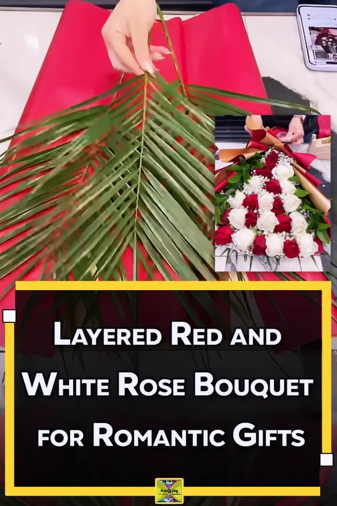 A luxury layered bouquet made with red and white roses, baby’s breath, palm leaves, and green foliage, wrapped in red and gold paper for a romantic flower gift.