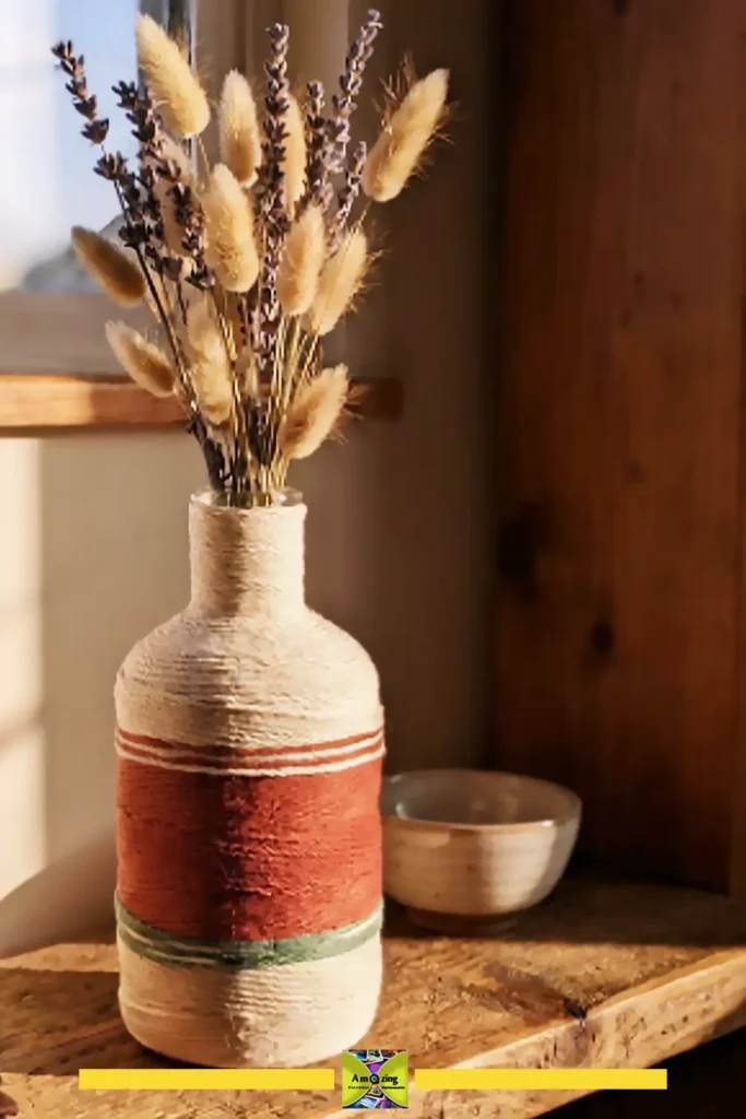 Yarn-wrapped bottle vase in cream and terracotta cotton holding dried summer flowers