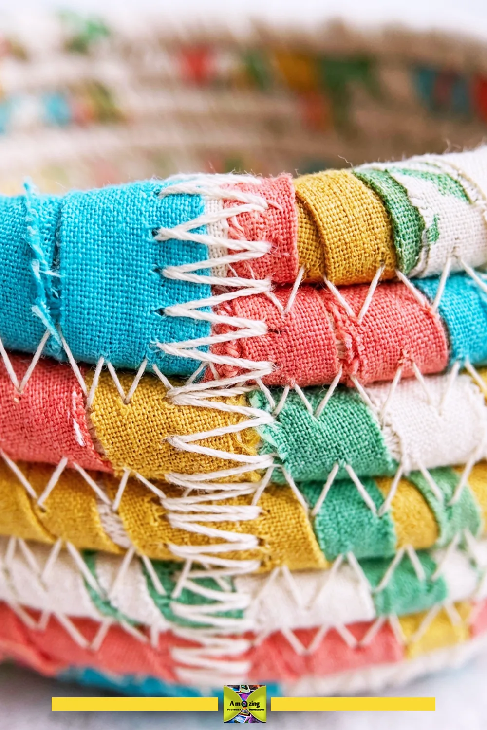 Close-up of a coiled basket with multicolored fabric strips joined by zigzag white stitches.