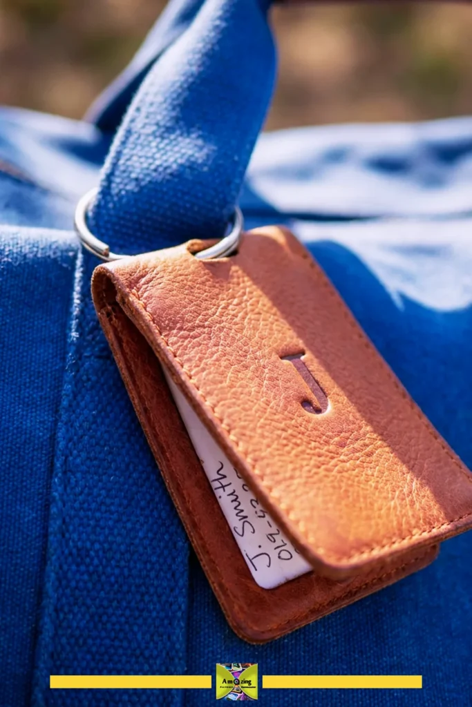 Close-up of a brown leather luggage tag with the letter J on a blue fabric bag