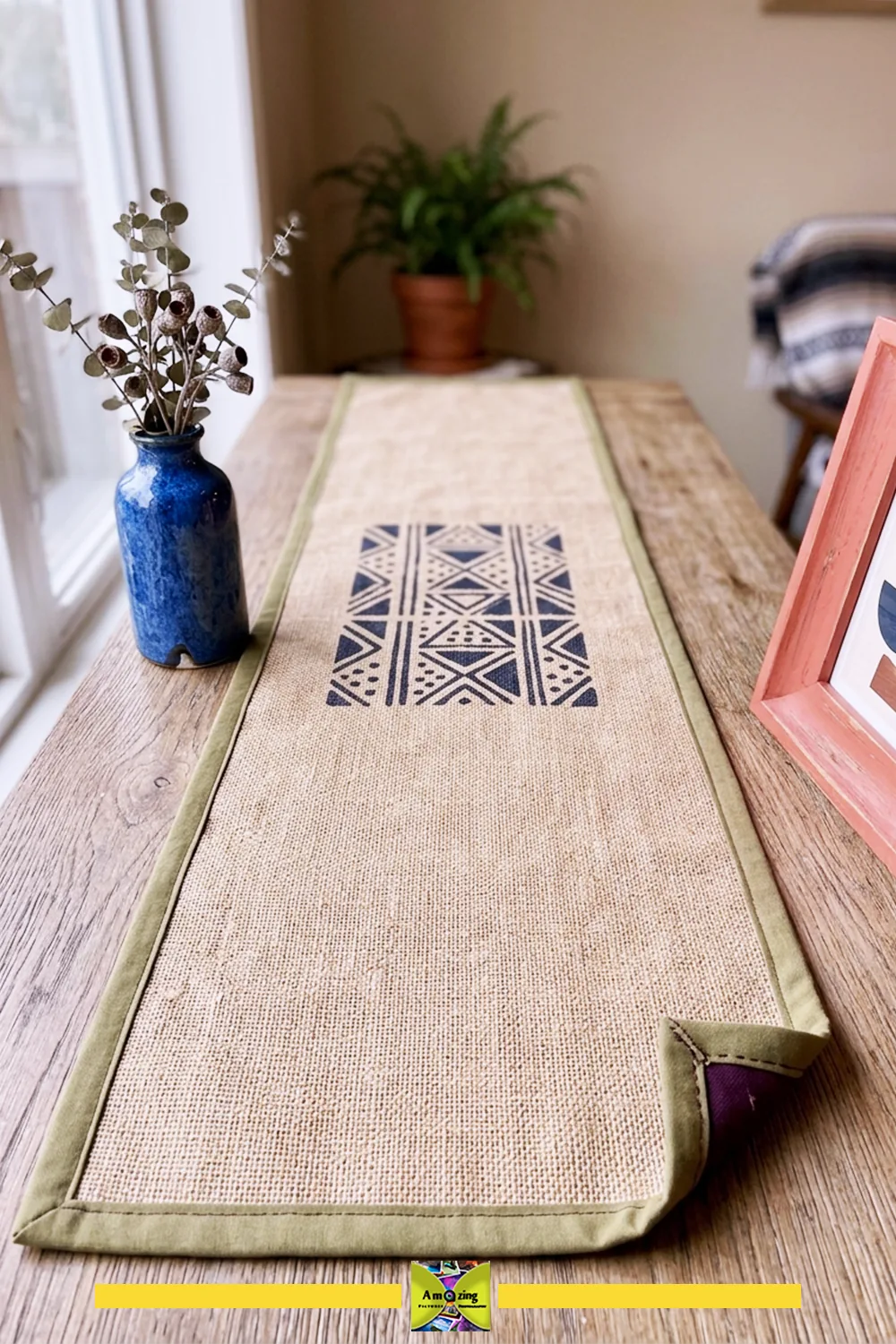 Handmade jute console table runner with geometric pattern, flat ends, and green trim on a wooden table.