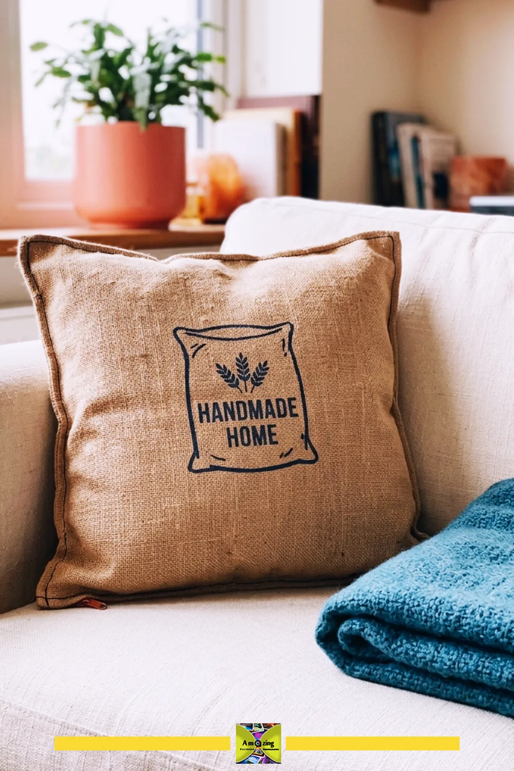 Burlap cushion with 'Handmade Home' print on a neutral sofa beside a blue throw blanket