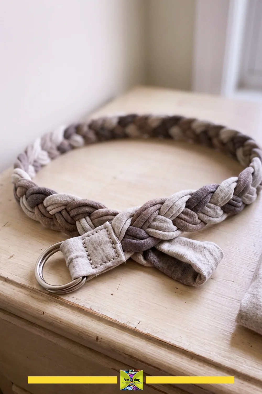 Handmade braided belt crafted from upcycled t-shirt fabric with a metal D-ring closure on a wooden surface.