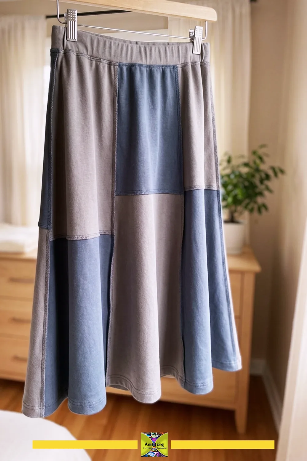 Patchwork jersey skirt in blue and gray tones hanging on a wooden hanger indoors.