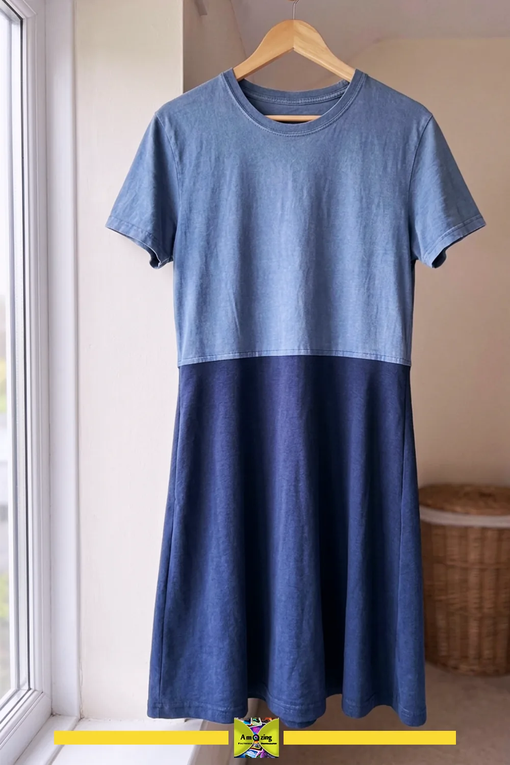 Handmade two-tone swing dress made from two shirts, hanging on a wooden hanger by a window.