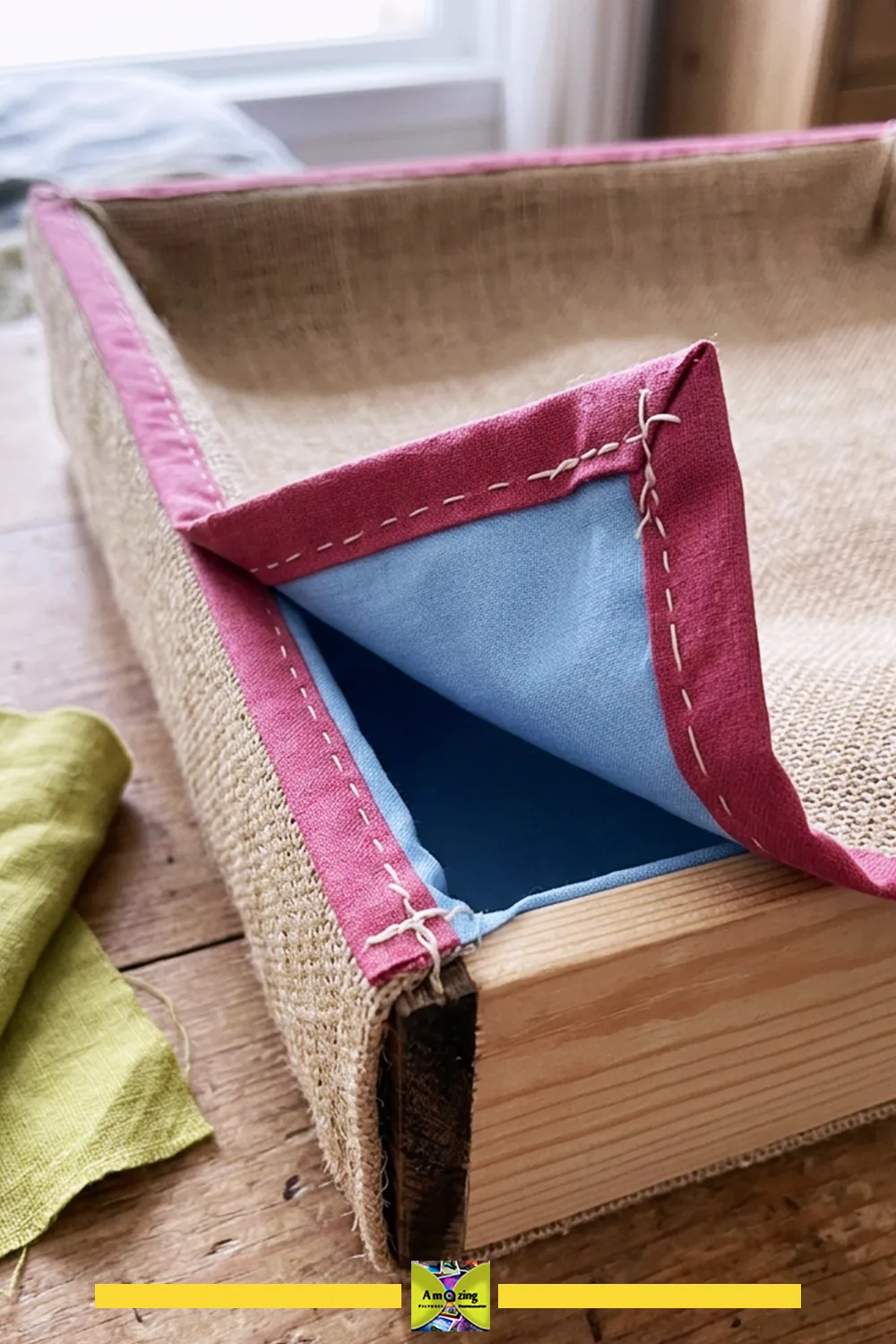 Close-up of a handmade fabric sleeve with pink edge and blue lining fitted over a wooden drawer bin.