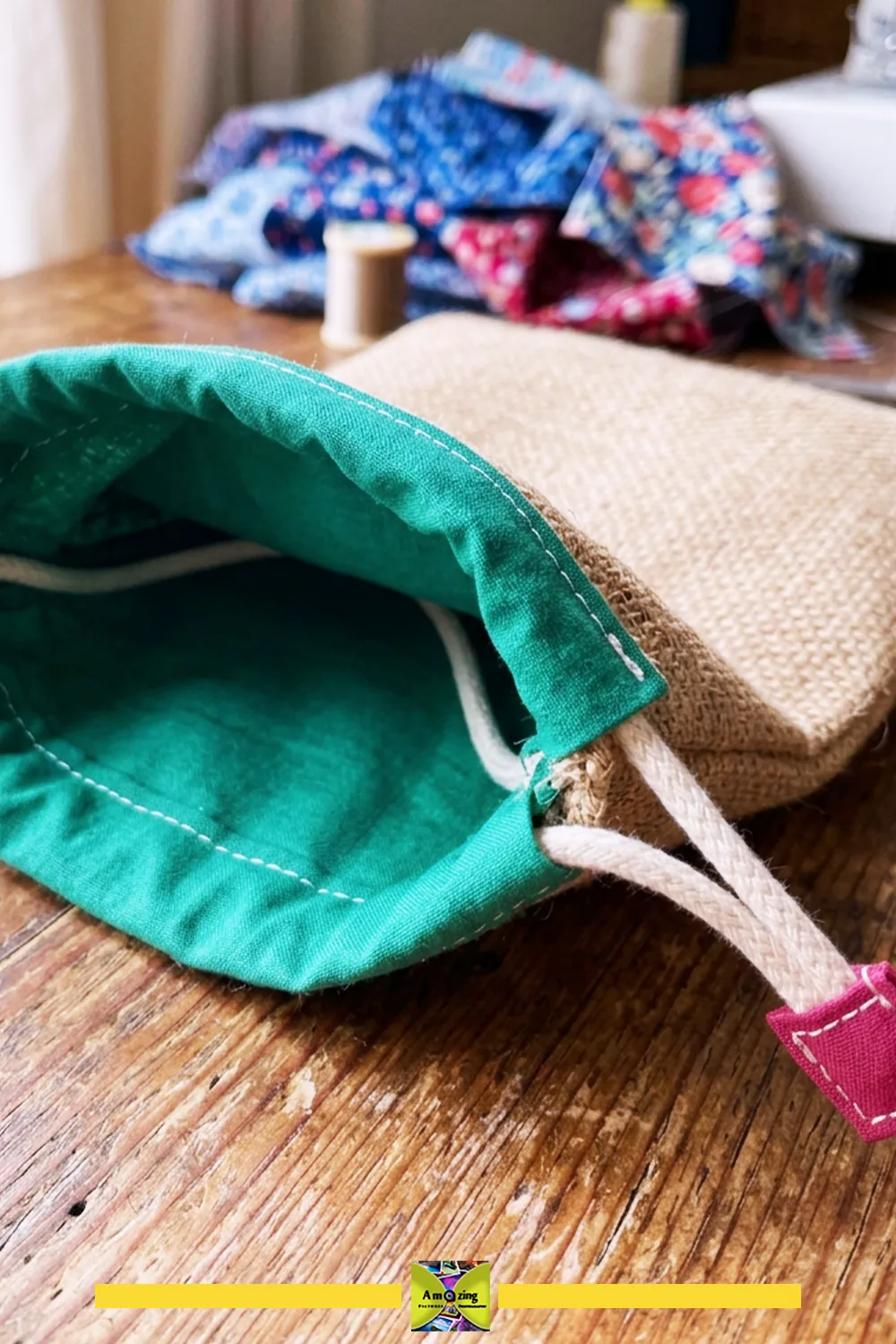 Close-up of a handmade drawstring sack with green lining, cord, and stitched cord end on a wooden table.