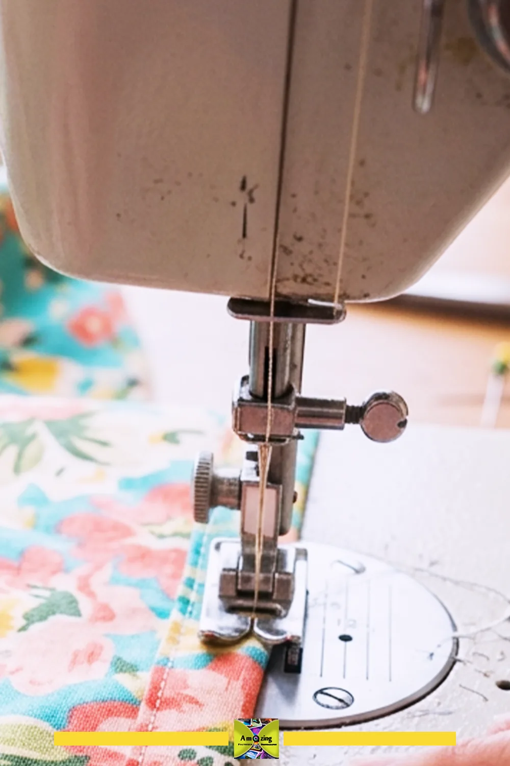 Close-up of a sewing machine stitching a double-fold hem on floral fabric