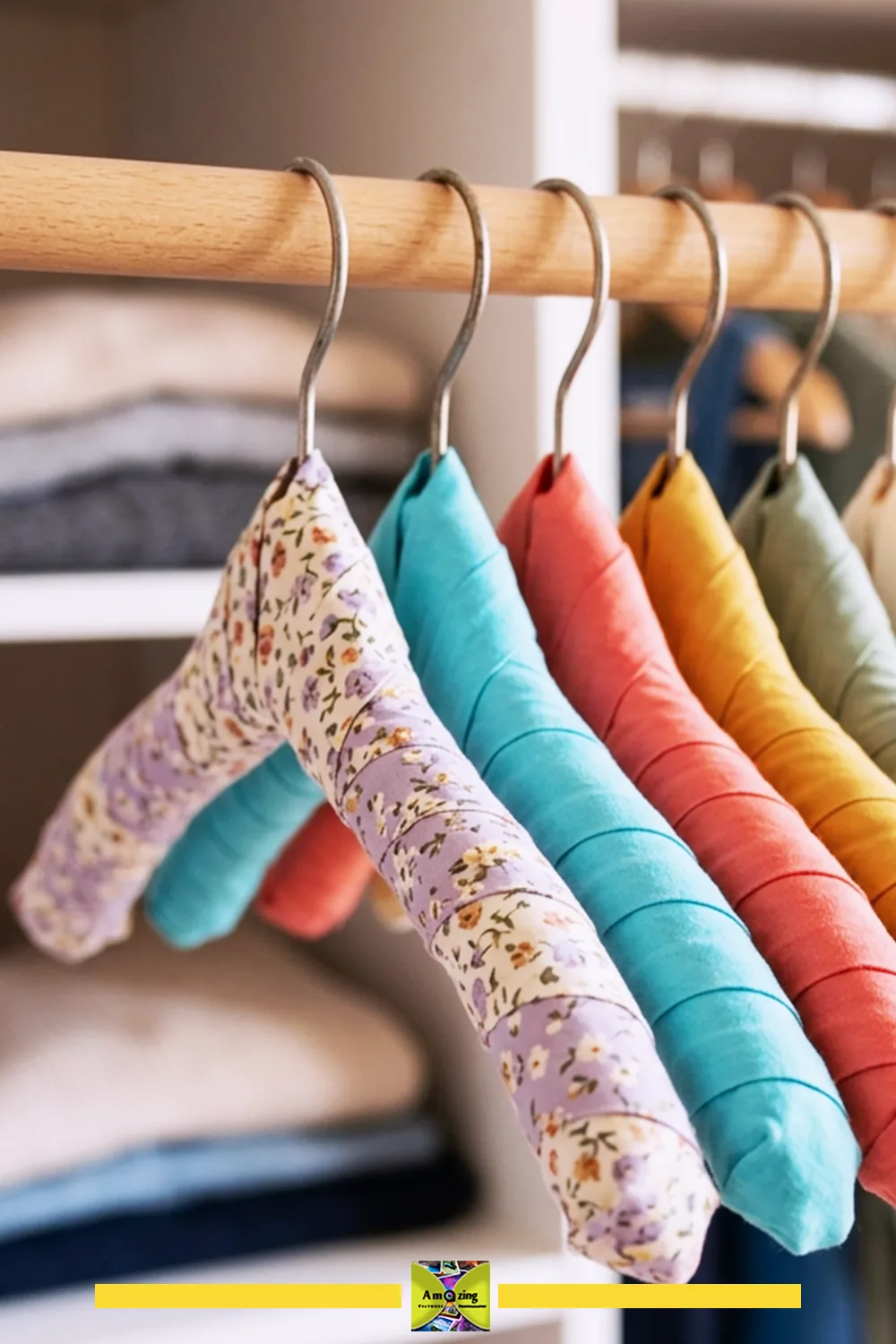 A set of padded hangers wrapped in colorful and floral fabric hanging on a wooden closet rod.