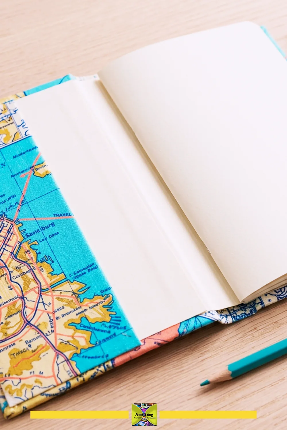 Open travel journal inside a colorful map-patterned jacket beside a teal pencil.