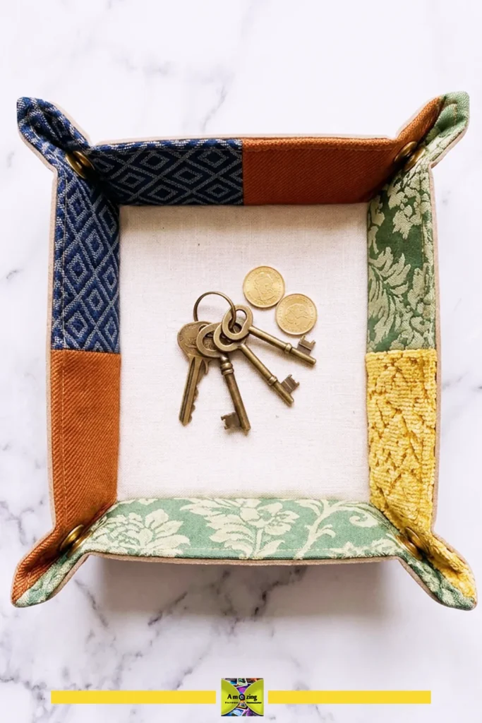 Fabric catchall tray holding a set of vintage keys and three coins on a marble surface.