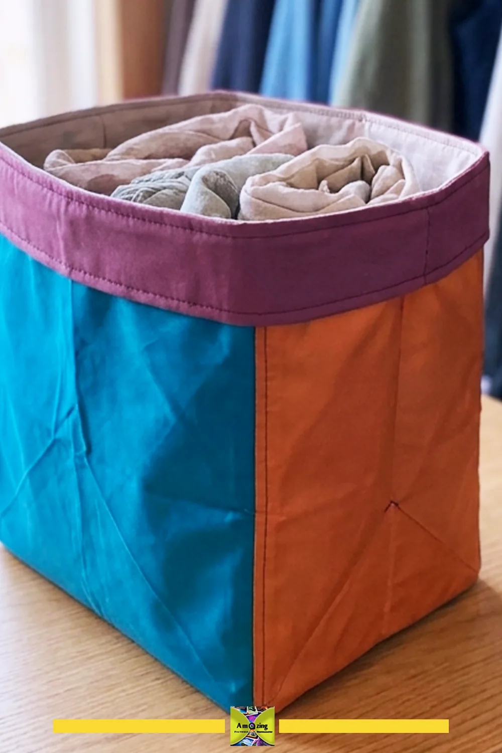 Colorful fold-flat closet storage bin filled with rolled towels on a wooden surface.