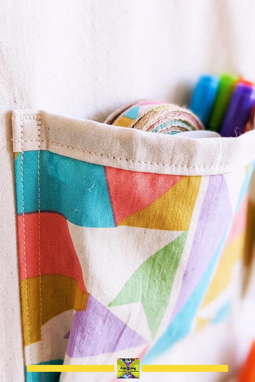 Close-up of a colorful fabric organizer pocket holding craft supplies like ribbon and markers.