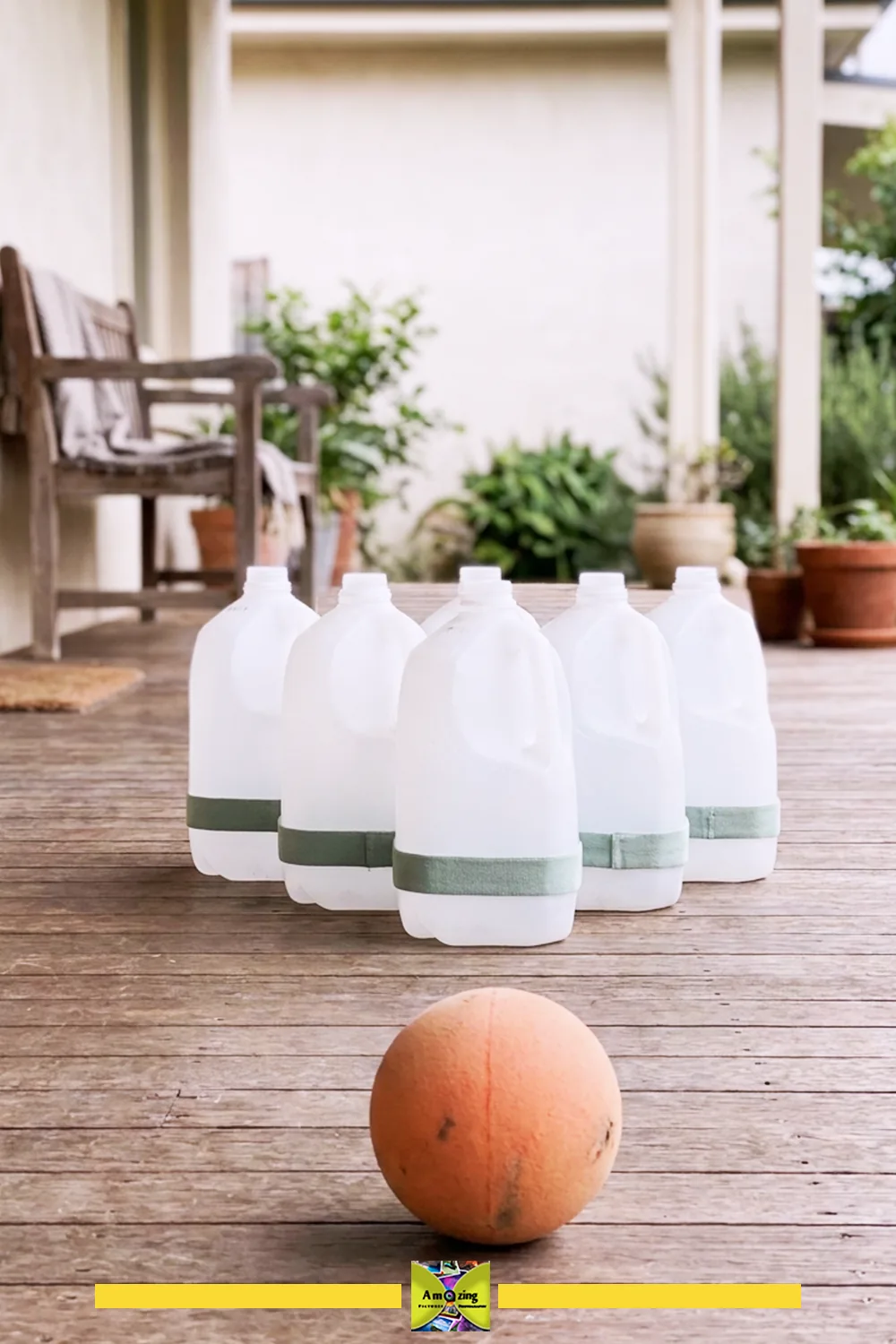 Homemade bowling pins made from plastic jugs and a ball on a wooden porch