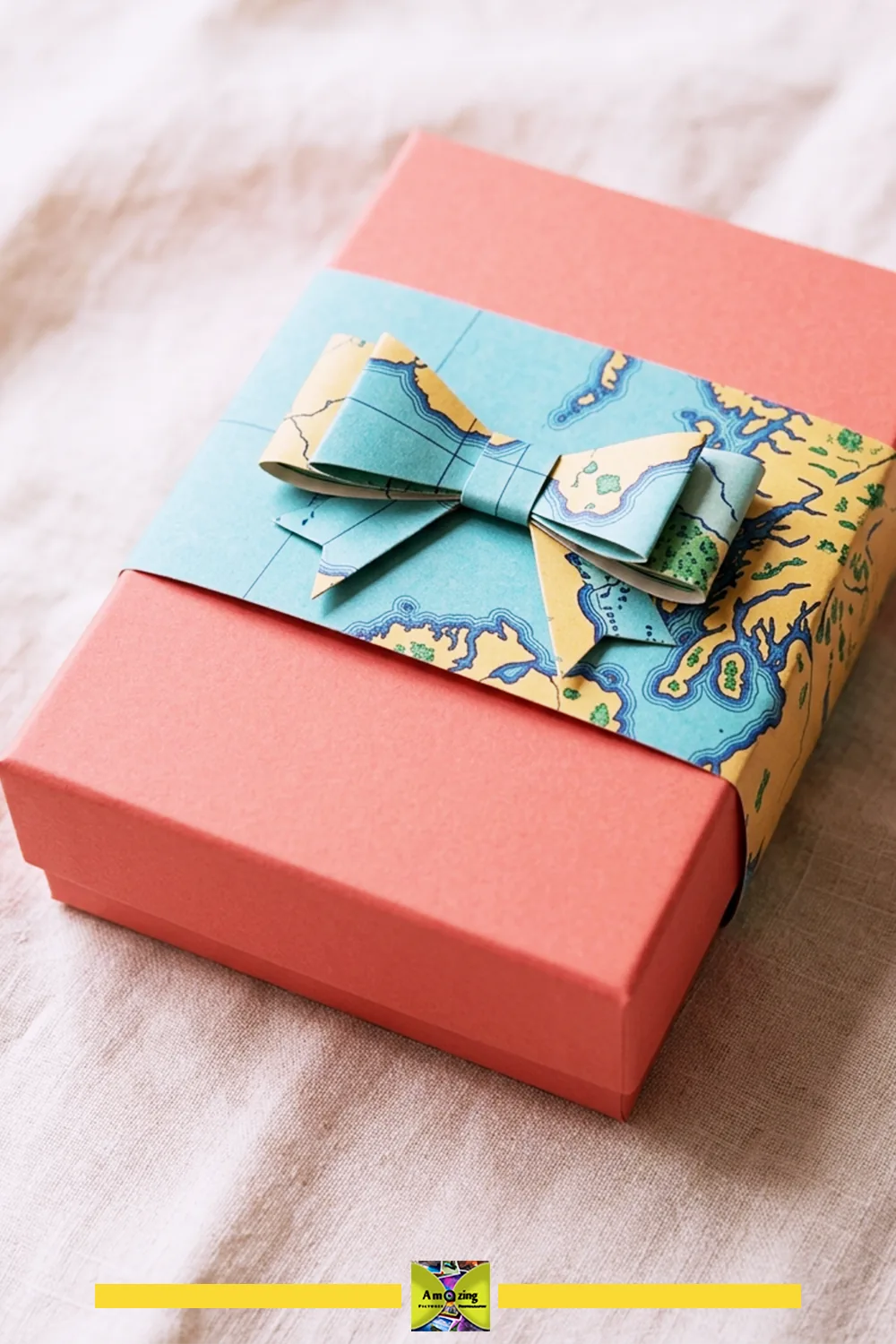 Coral gift box wrapped with a map-paper band and folded paper bow.