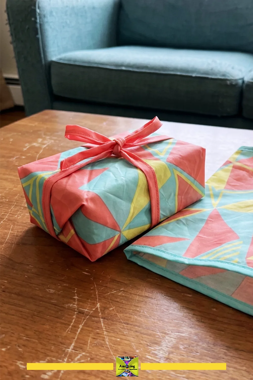 Reusable fabric gift wrap and matching flat gift bag with colorful geometric patterns on a table.