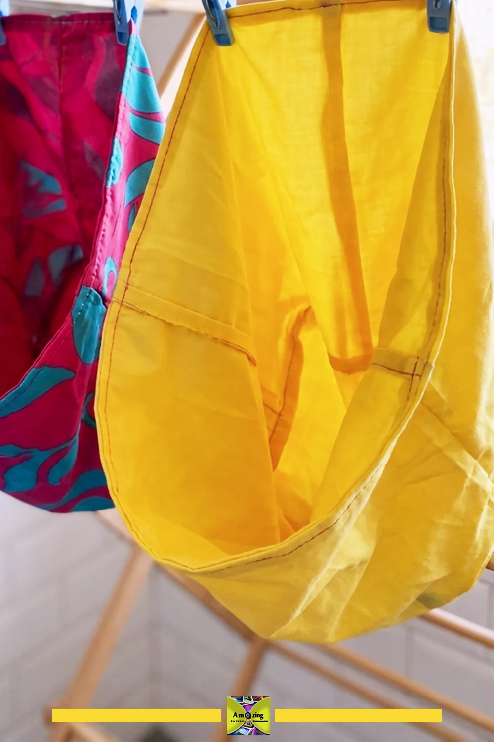 Yellow fabric pouch lining air-drying on a rack next to a colorful red and blue pouch