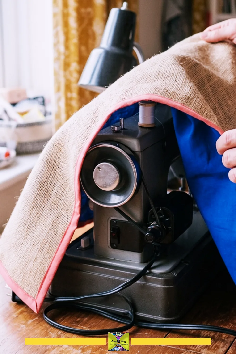 Person fitting a burlap and fabric cover over a vintage sewing machine on a wooden table