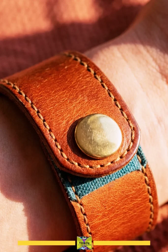 Close-up of a brown leather cuff bracelet with a brass snap button on a wrist.
