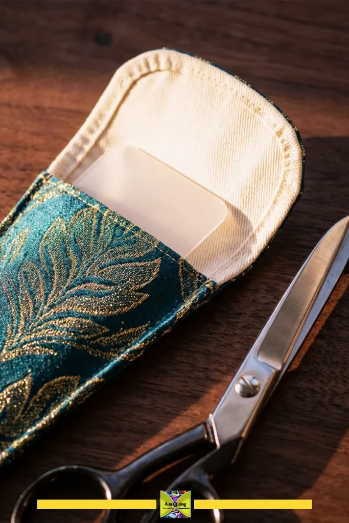 Close-up of a fabric scissors sheath with a rigid insert and metal scissors on a wooden surface.