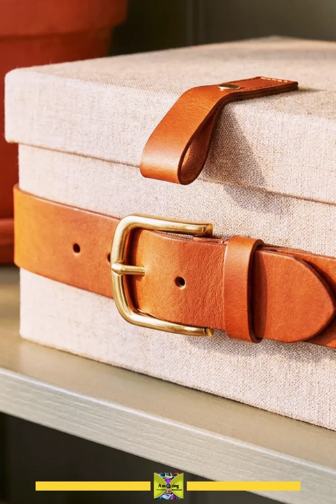 Fabric storage box secured with a tan leather belt and matching leather lid pull tab