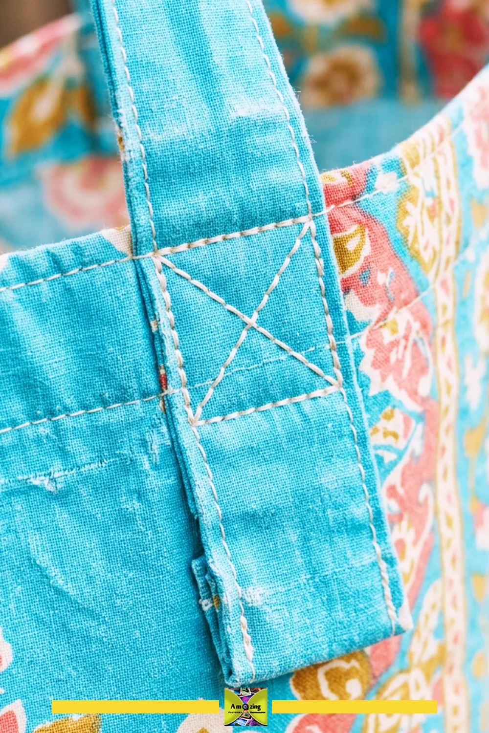 Close-up of a blue fabric gift bag showing reinforced stitching on the handle attachment.