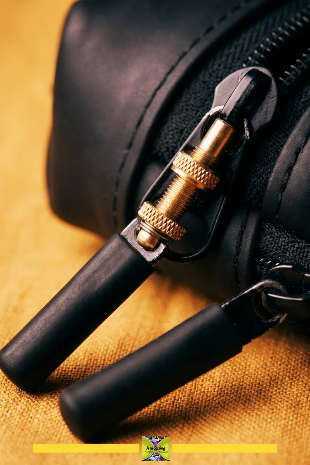 Close-up of a black rubber zippered pouch showing enclosed zipper ends and a metal valve used as the zipper pull