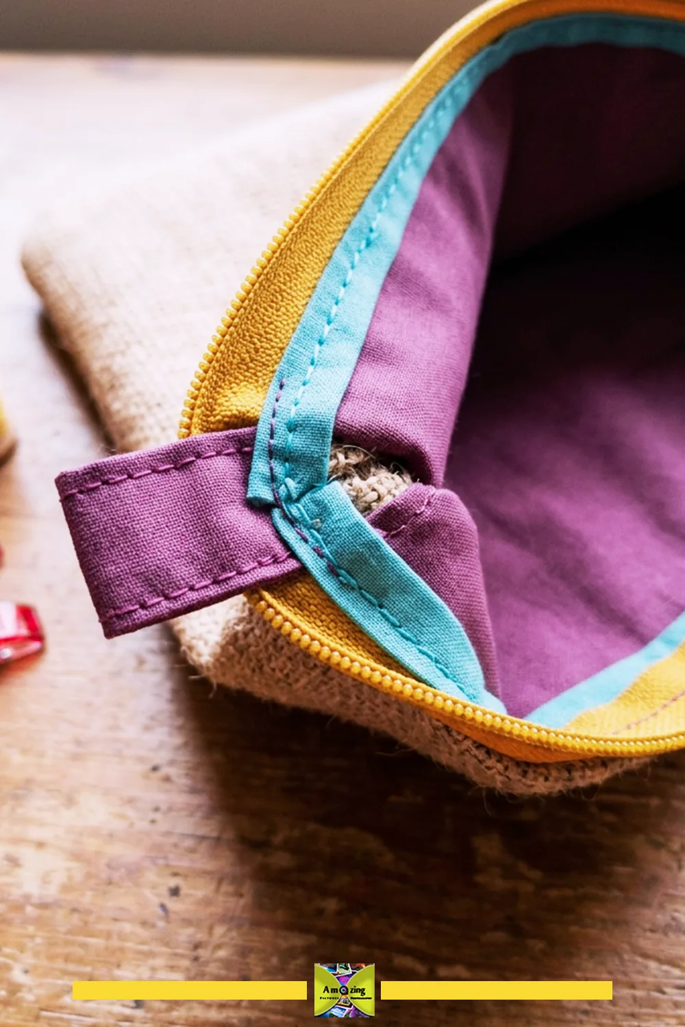 Close-up of a zippered pouch with a yellow zipper, purple fabric, and blue bound seam.