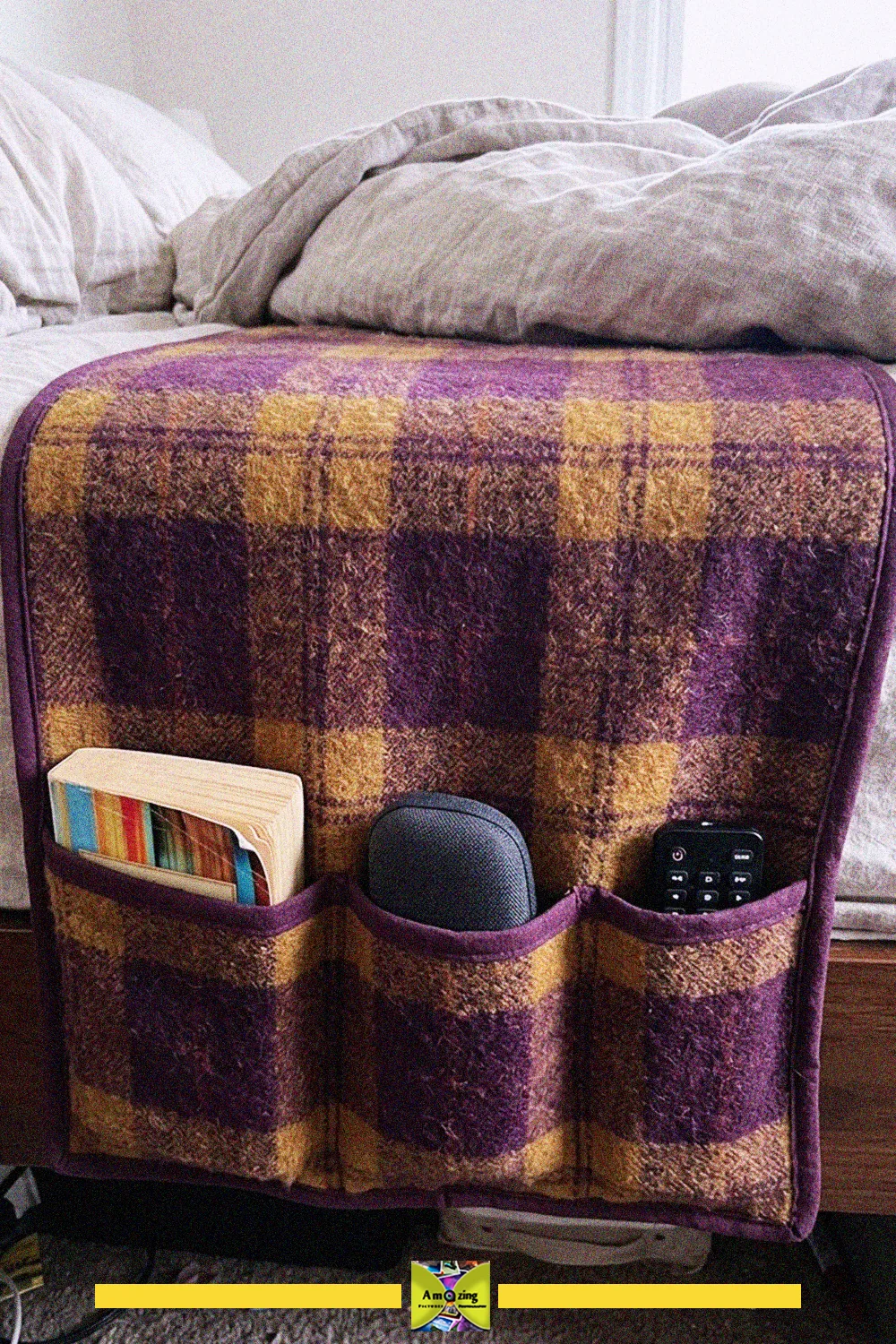 Purple plaid bedside pocket organizer made from an old blanket, holding a book, speaker and remote