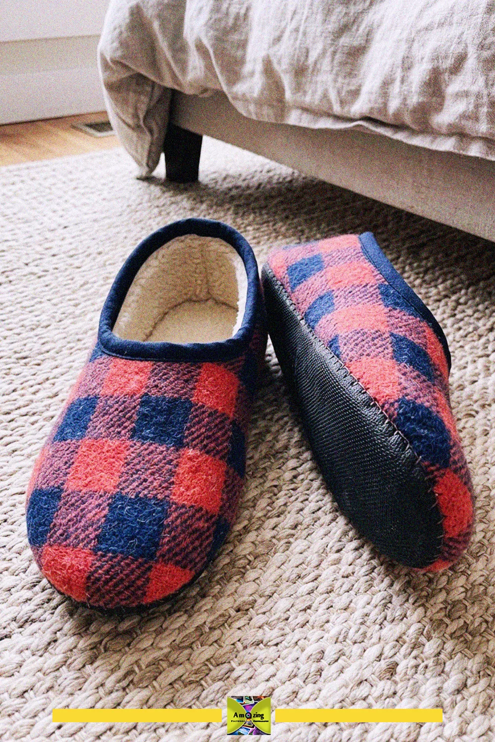 Pair of handmade red and navy plaid slippers made from blanket fabric with non-slip soles on a rug