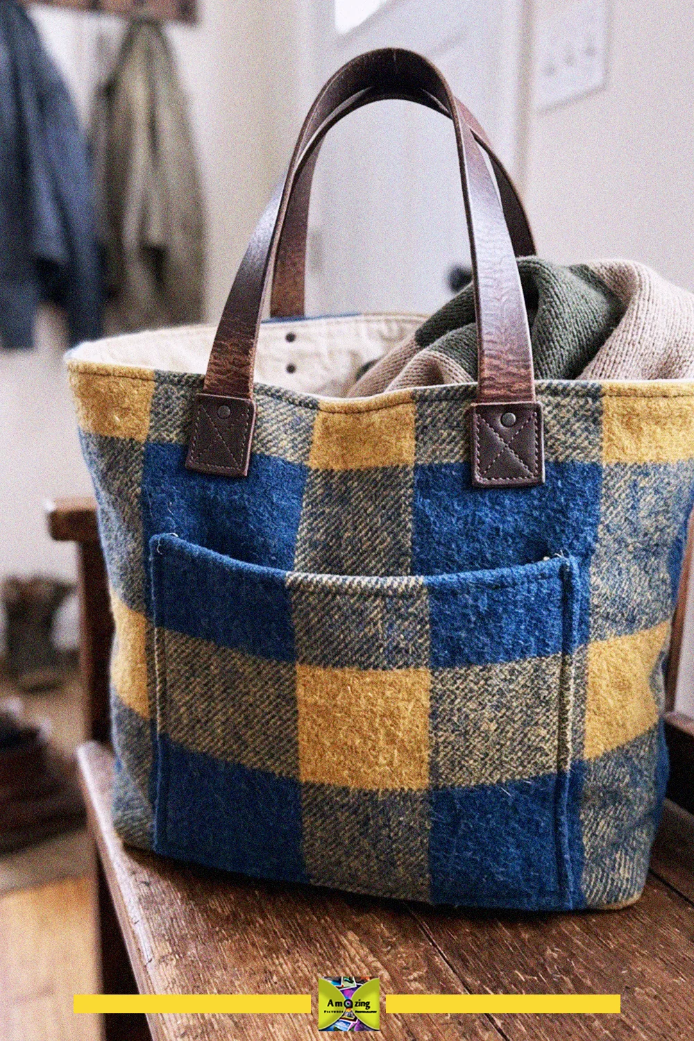 Blue and yellow plaid tote bag made from an old blanket with leather belt handles on a wooden bench