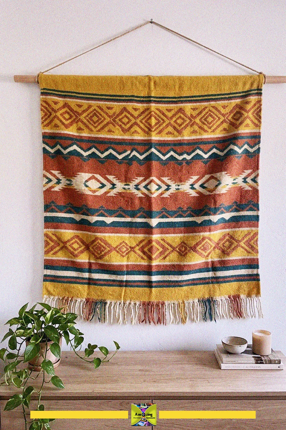 Striped blanket wall hanging in orange, yellow and teal with fringe, hung above a wooden console