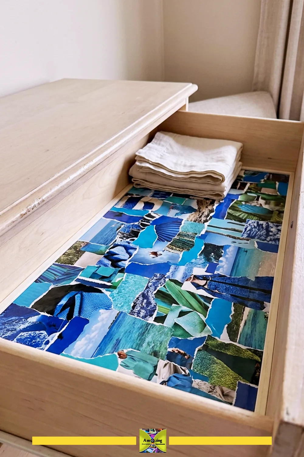 Open wooden drawer with a vibrant blue and green magazine collage liner and folded linens inside.