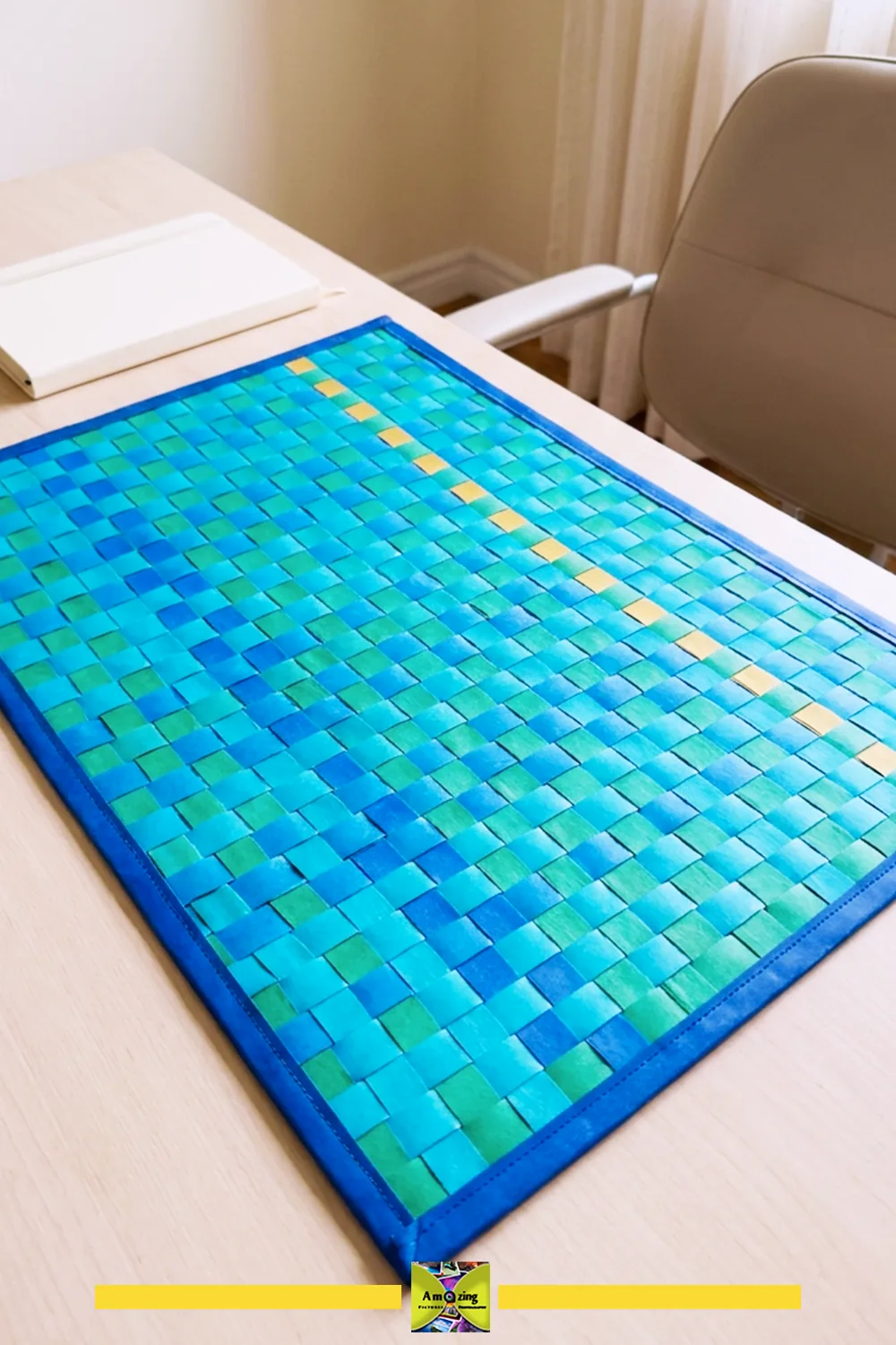 Handmade woven desk mat with blue and green strips, neatly finished edges, on a light wood desk